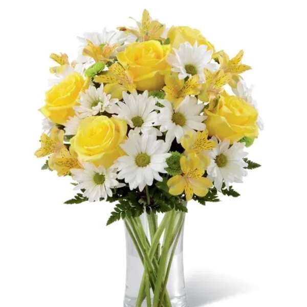 Yellow roses and white daisies in a clear glass vase