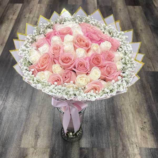 Bouquet of pink and white roses with baby's breath in a silver vase