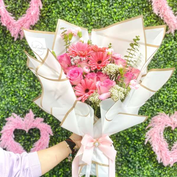 Pink bouquet with roses and gerbera daisies wrapped in white paper