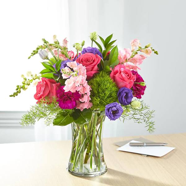 Mixed pink, purple, and white flowers in a clear glass vase
