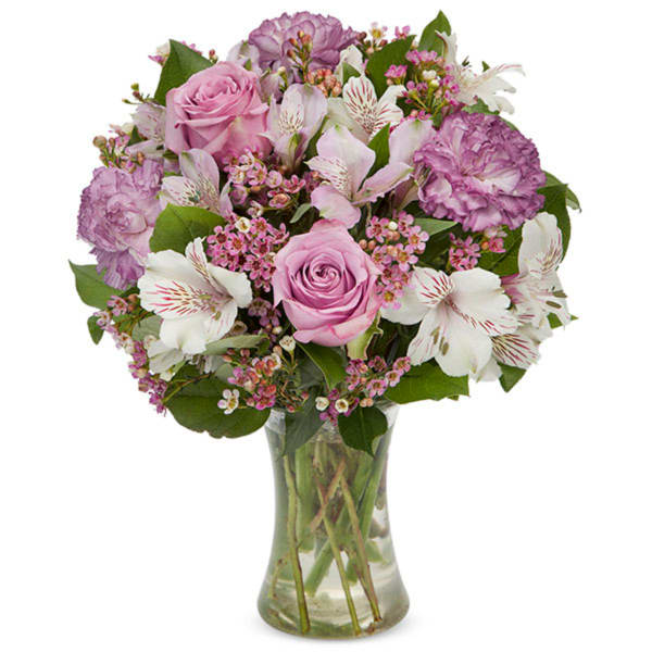 Pink roses and purple flowers arranged in a clear glass vase