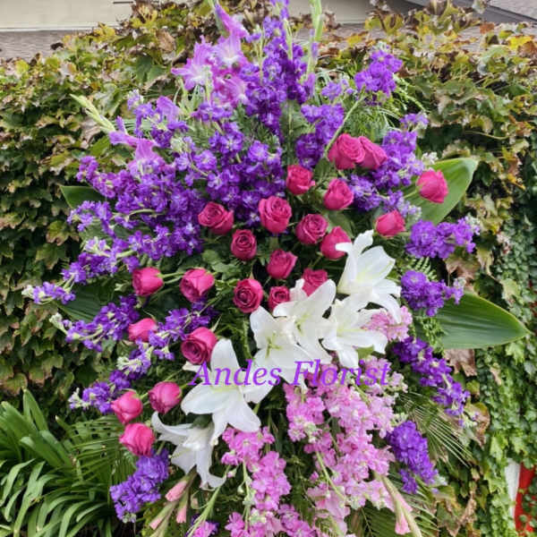 Large standing floral spray with pink roses, white lilies, and purple flowers