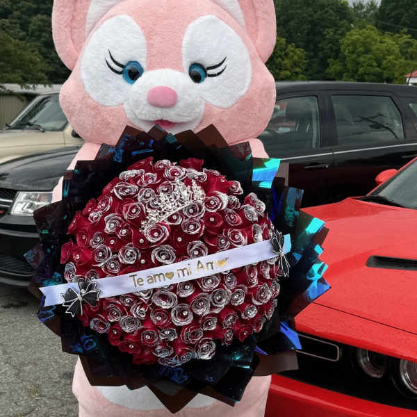 Pink bunny mascot holding a red rose bouquet with a ribbon
