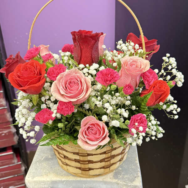 Basket arrangement of red and pink roses with white baby's breath