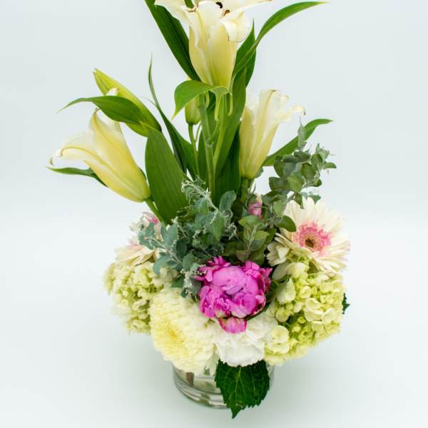 Tall bouquet of pale lilies and mixed pastel flowers in a glass vase