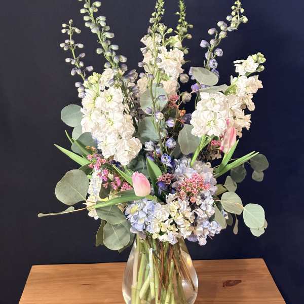 Tall pastel bouquet in a clear glass vase with pink tulips and white blooms