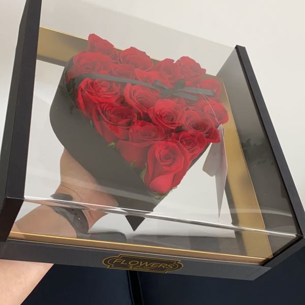 Heart-shaped box of red roses under a clear lid