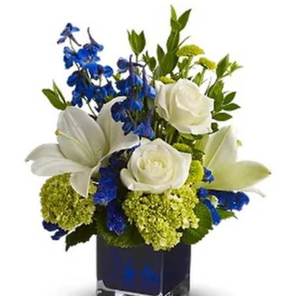 White lilies and roses with blue flowers in a square glass vase