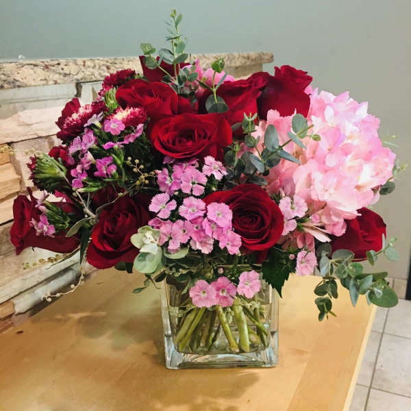 Bouquet of red roses and pink flowers in a clear glass vase