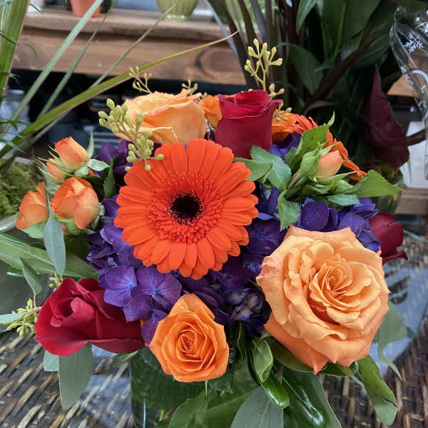 Orange gerbera and roses in a glass vase