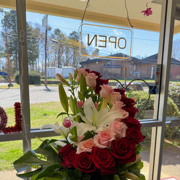 Bouquet of red and pink roses with white lilies in a black vase