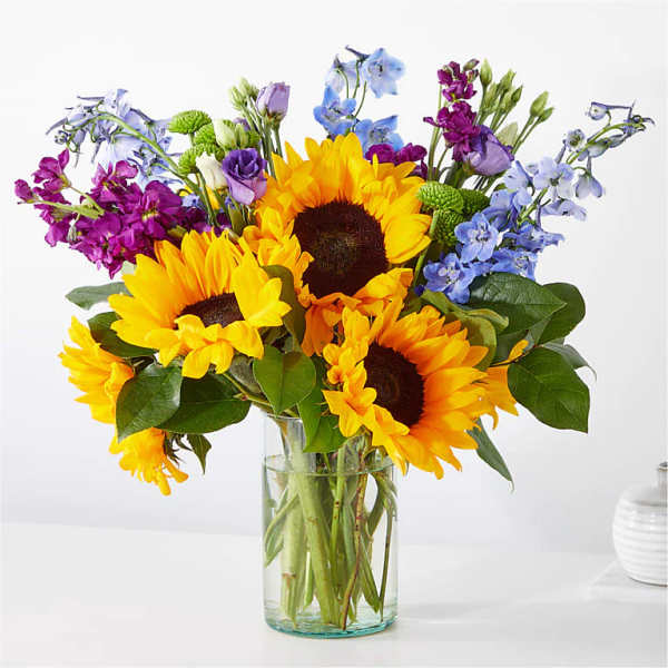 Sunflowers and purple-blue flowers in a clear glass vase