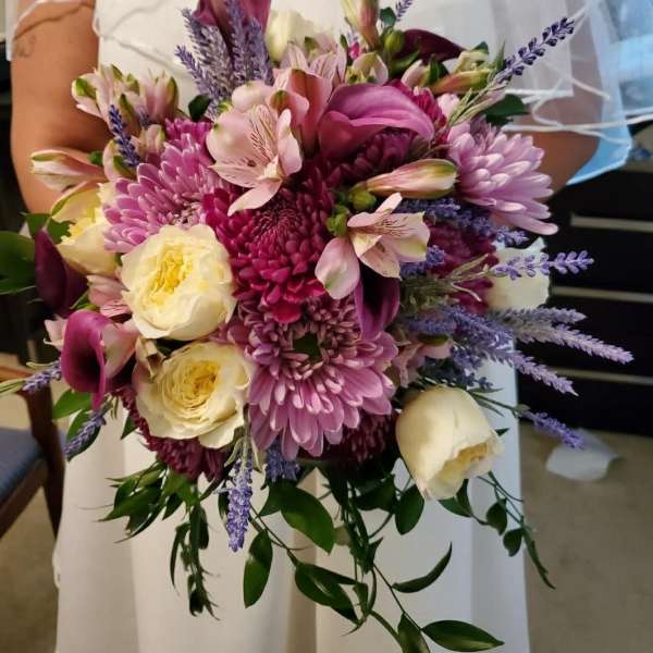 Bride holding a pink and cream bouquet with purple accents