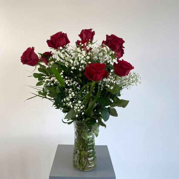 Red roses in a clear glass vase with baby's breath