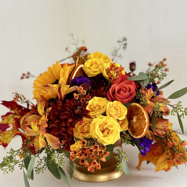 Autumn bouquet with yellow and red roses in a gold vase