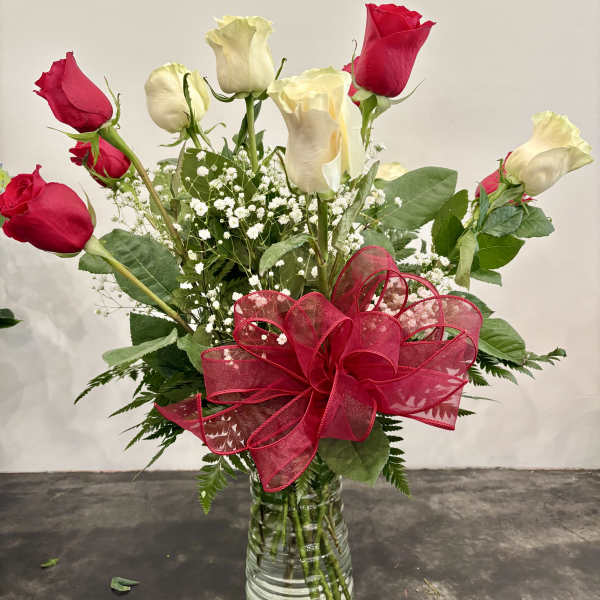 Red and white roses in a glass vase with a large red ribbon