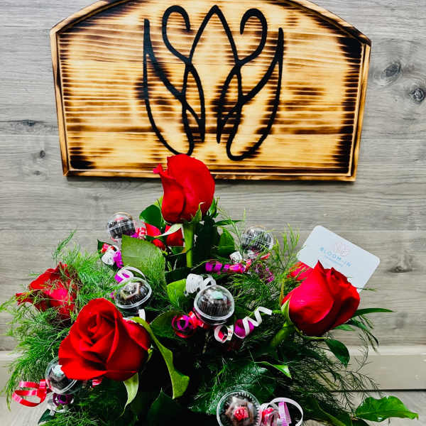 Bouquet of red roses with candy accents and ribbon in a glass vase