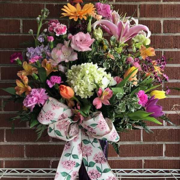 Large mixed flower arrangement with a floral ribbon bow