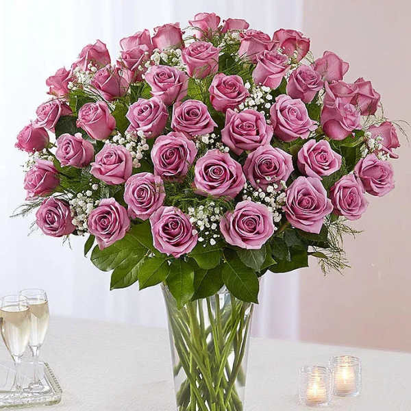 Pink roses arranged in a clear glass vase with baby's breath