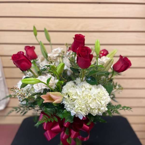Red roses and white hydrangea in a glass vase with a ribbon