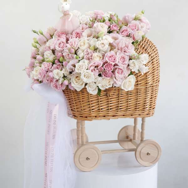 Pink and white rose bouquet in a wicker baby carriage with a small doll topper