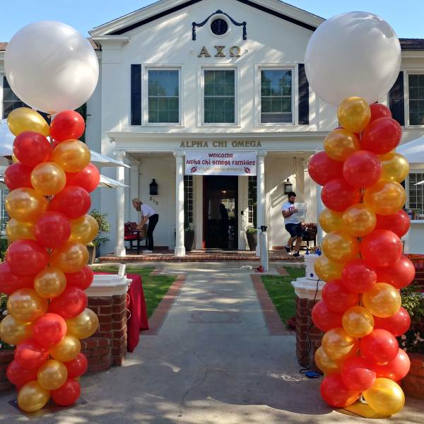 Red, orange, and gold balloon columns frame a house entrance