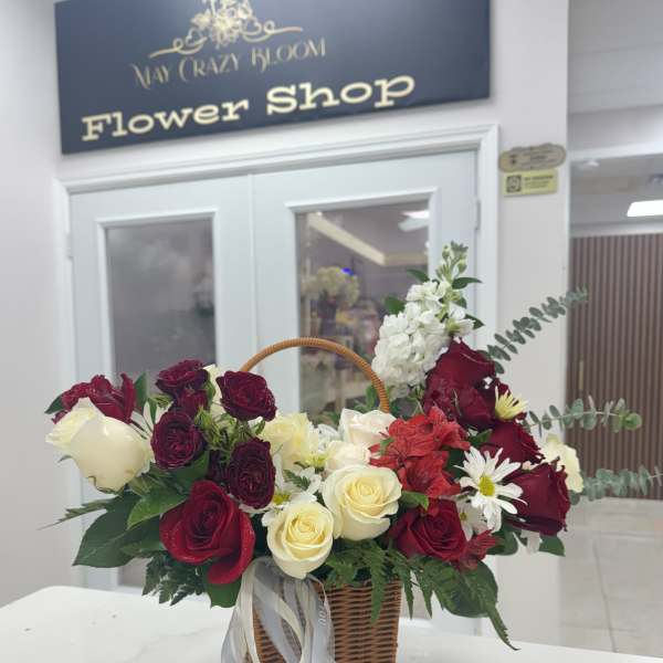 Basket arrangement of red and white roses with daisies