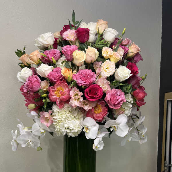 Large bouquet of pink, white, and peach flowers in a tall green vase