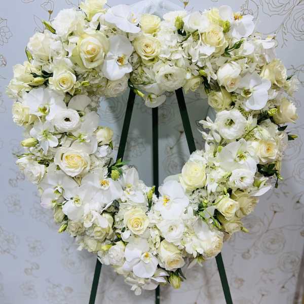 Heart-shaped white floral wreath on a stand