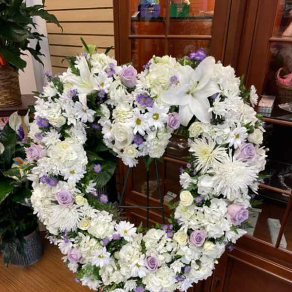 Heart-shaped white floral wreath on a stand with lavender accents