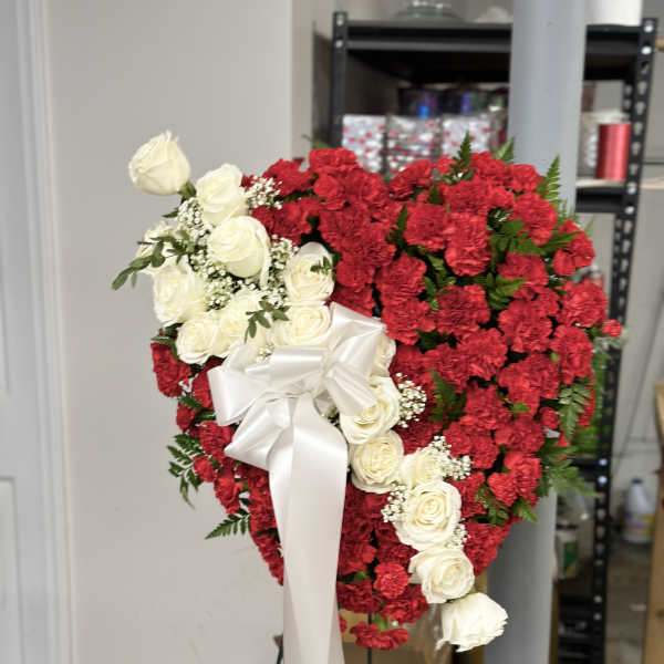 Heart-shaped red and white floral wreath with a white ribbon bow