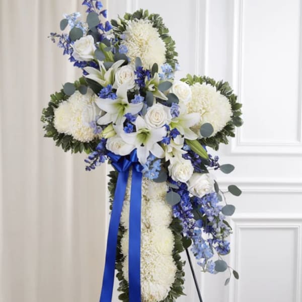 White floral standing spray with blue accents and ribbon
