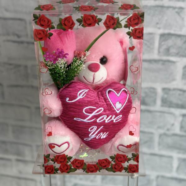 Pink teddy bear in a clear gift box with a heart-shaped "I Love You" decoration