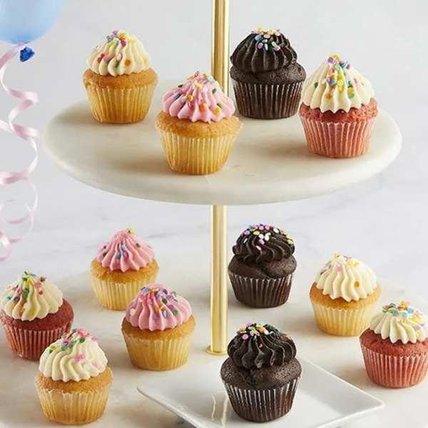 Cupcakes on a two-tier stand with pastel balloons at the side