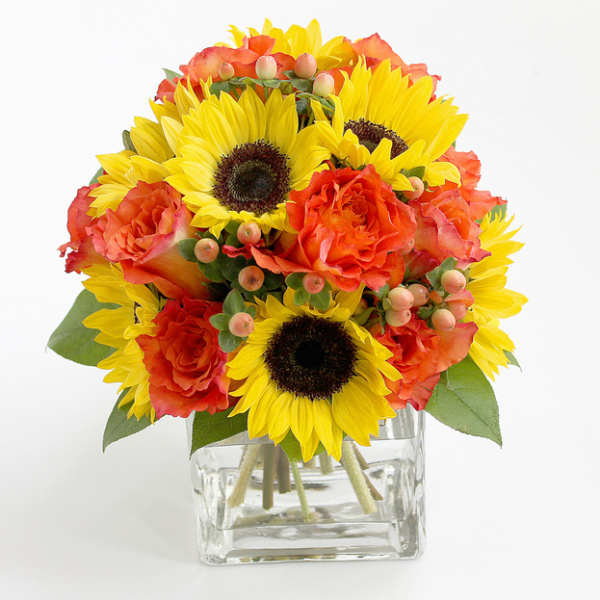 Sunflowers and orange roses in a clear glass vase