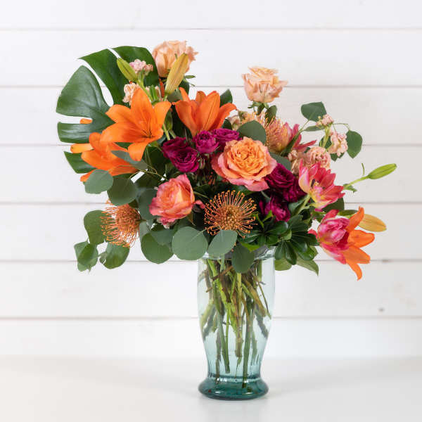 Mixed bouquet of orange and pink flowers in a glass vase