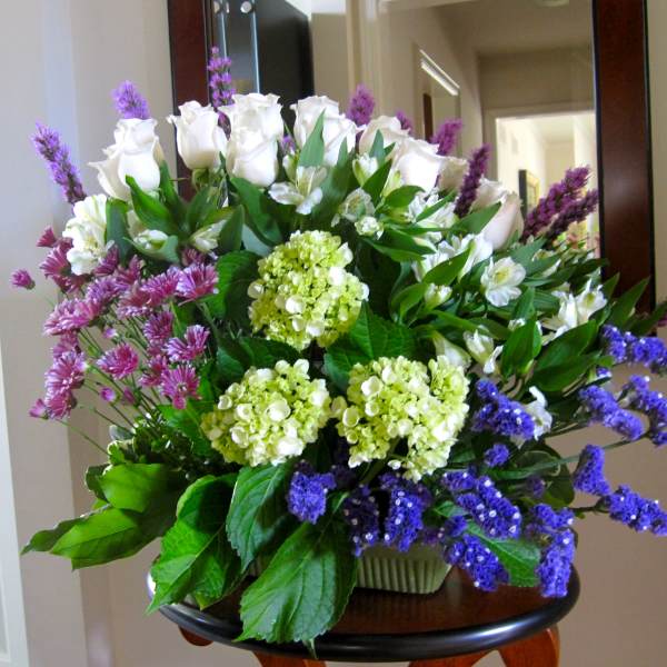 Bouquet of white roses, hydrangeas, and purple flowers in a vase