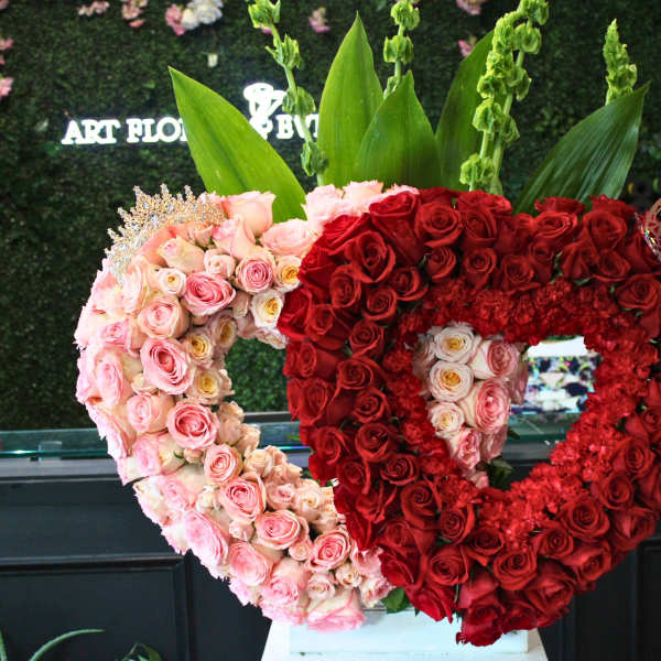 Heart-shaped rose arrangements in pink and red with tall green leaves behind them