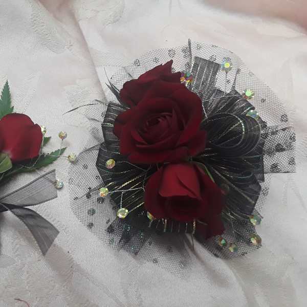 Two burgundy rose floral accessories on white fabric