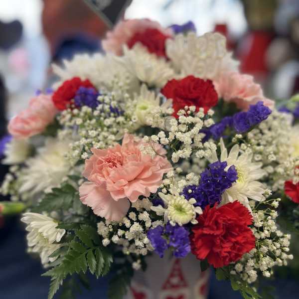 Mixed bouquet of carnations, daisies, and baby's breath in a white container