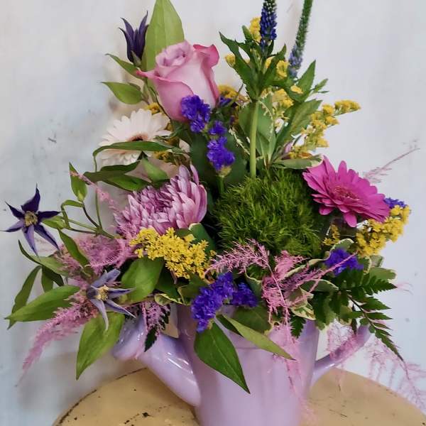 Mixed bouquet in a lavender watering can with pink, purple, and white flowers