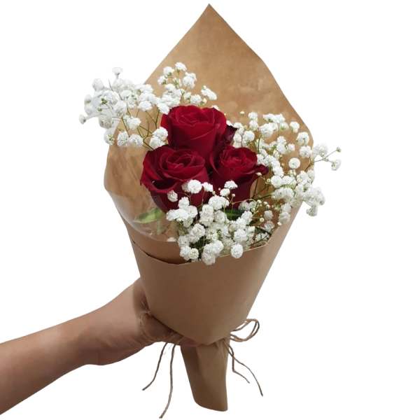 Bouquet of red roses and white baby's breath in brown paper wrap