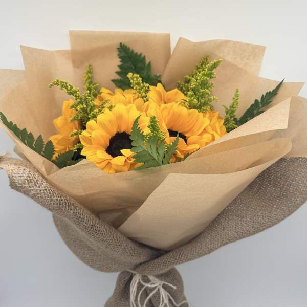 Bouquet of yellow sunflowers wrapped in brown paper and burlap
