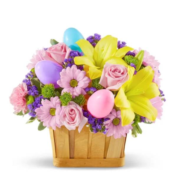 Basket of pink and yellow flowers with pastel Easter eggs