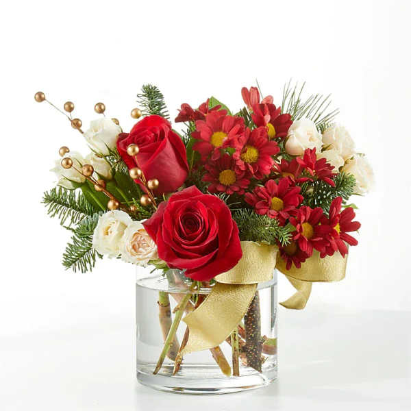 Red roses and red daisies in a clear glass vase with gold ribbon
