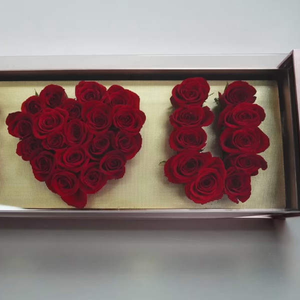 Red roses arranged in a rectangular display box spelling "I ♥ U"