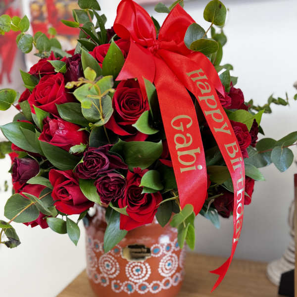 Red rose bouquet with a birthday ribbon in a decorated vase
