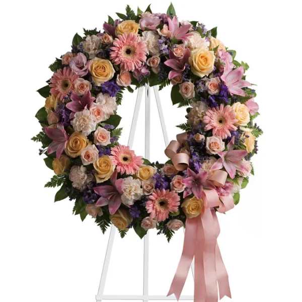 Pastel floral wreath with pink ribbon on a white stand