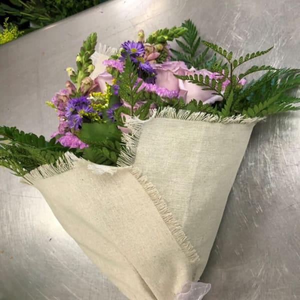Bouquet of pink roses and purple flowers wrapped in beige fabric
