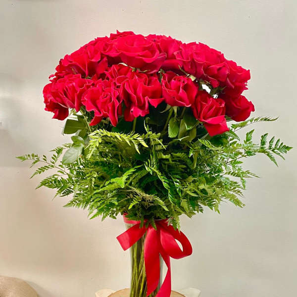 Red roses in a clear glass vase with a red ribbon